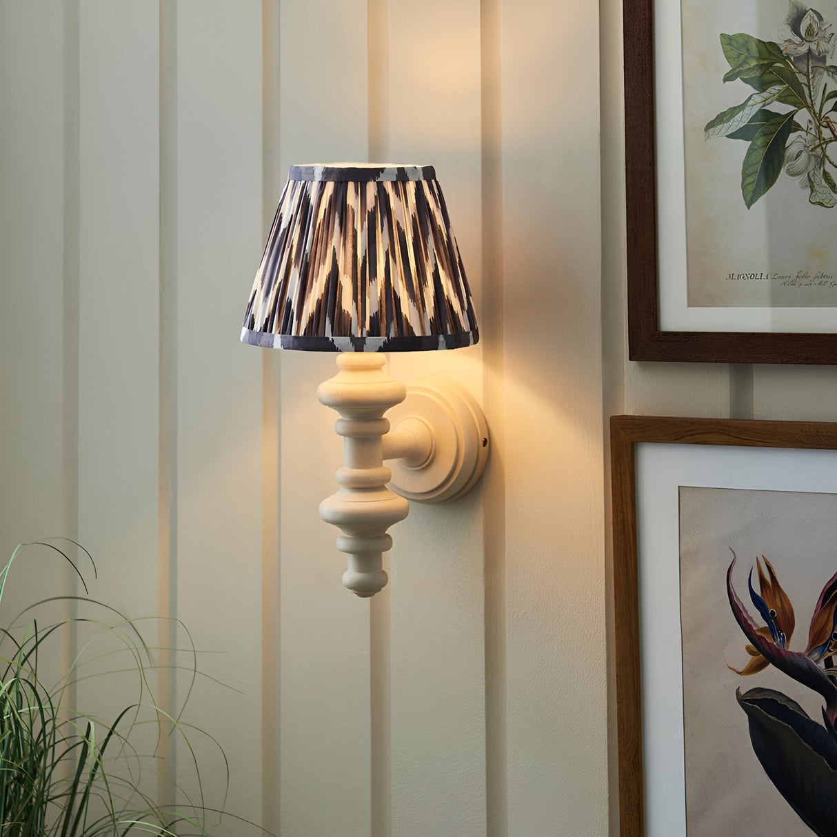 Endon Bevbury Zigzag wall light with turned white spindle and grey zigzag pleated shade, mounted on panelled wall beside framed botanical prints.