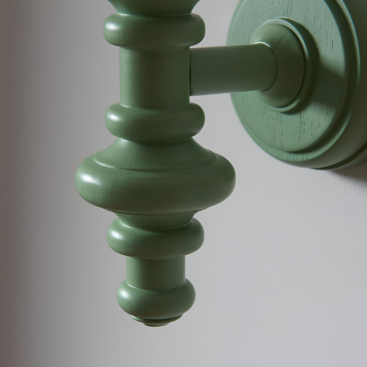 Close-up of the Endon Bevbury Zigzag wall light's turned wooden spindle in satin Cotswold green, mounted to a round wall plate.