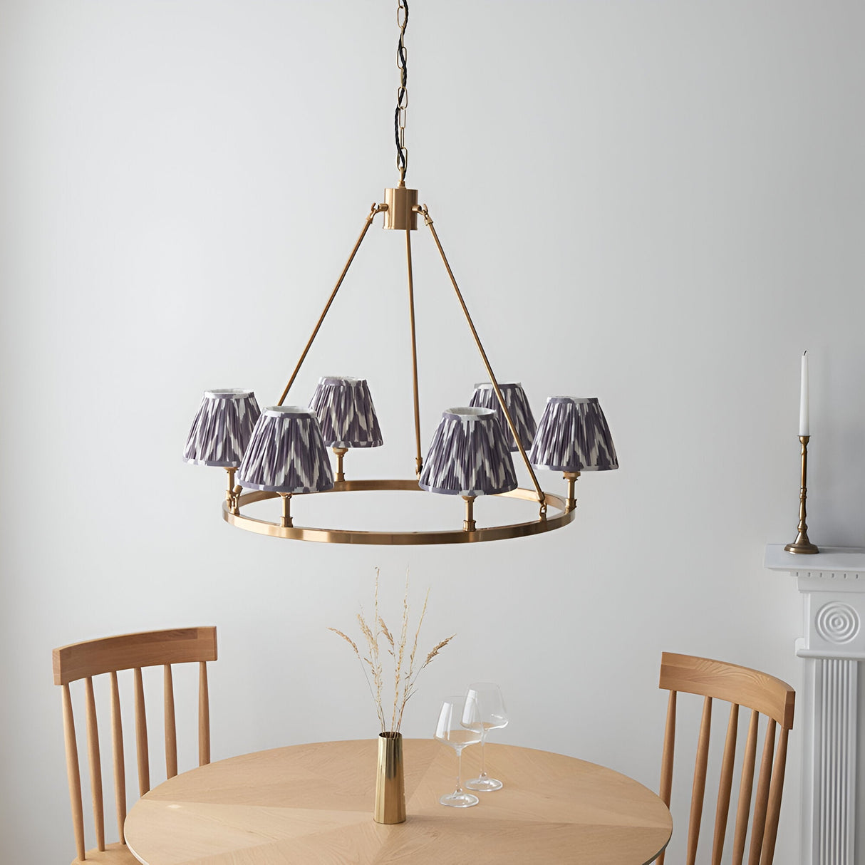 Endon Bevford Zigzag six-light hoop pendant in aged brass with pleated grey zigzag fabric shades, above a wooden dining table and chairs.