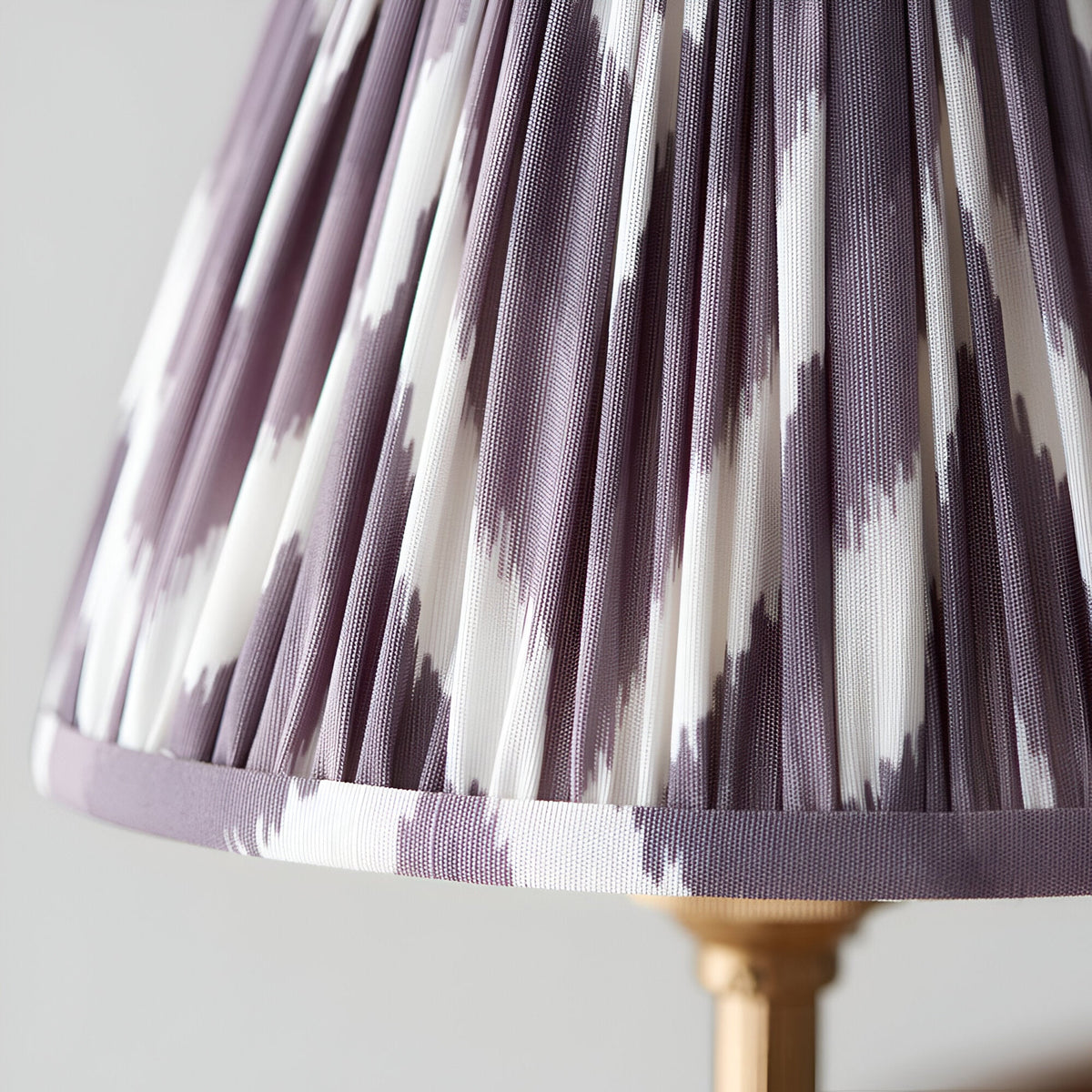 Close-up of an Endon Bevford Zigzag pendant shade in pleated pearl grey faux silk with a zigzag print and taped edge, on an aged brass fitting.