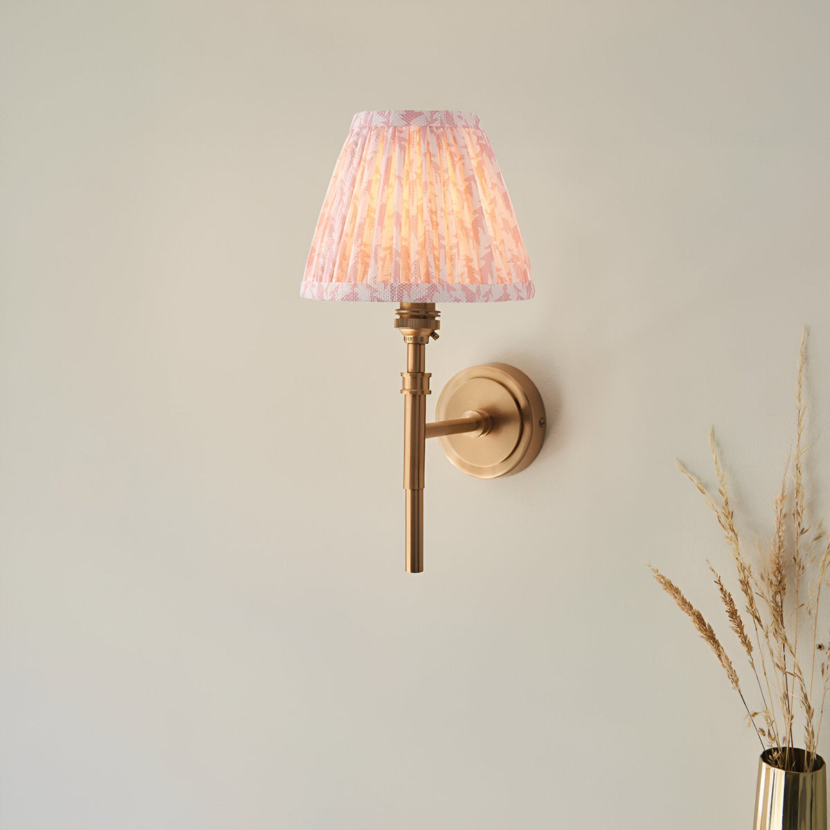 Bevford Leaf Wall Light in aged brass finish with a pleated tapered pink leaf-patterned fabric shade, shown against a plain light background.