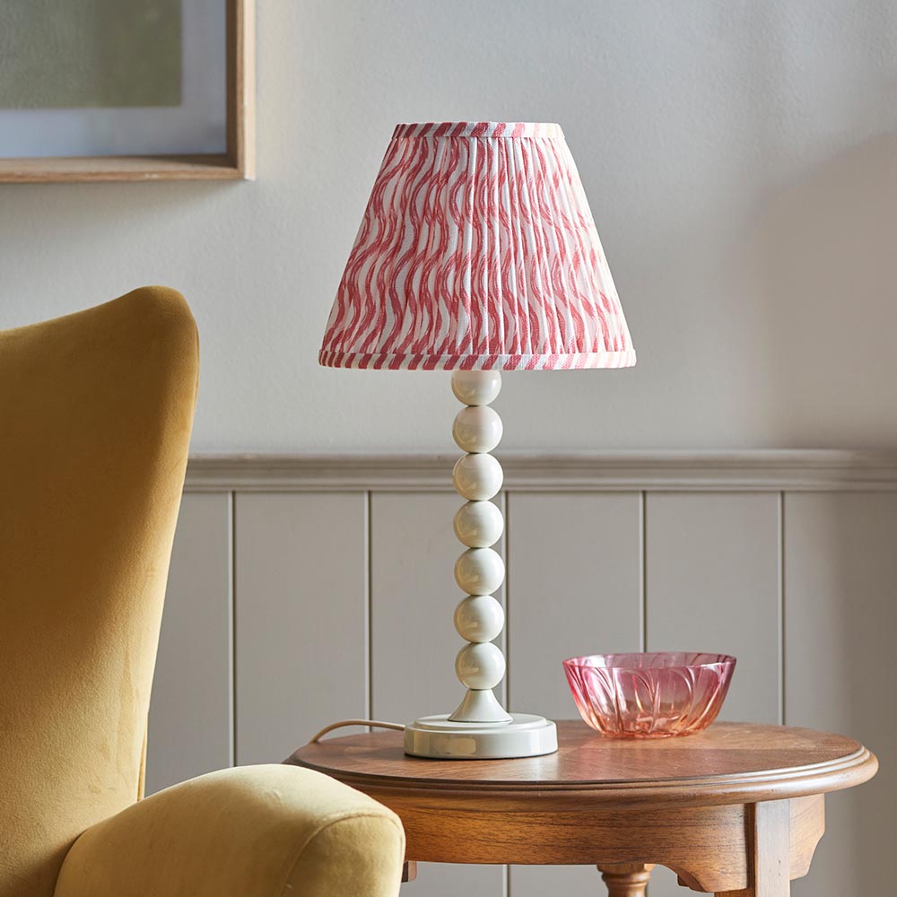 Endon Brenleigh Ripple table lamp with white stacked-sphere base and pink pleated ripple shade, on a wooden side table beside a pink glass bowl.