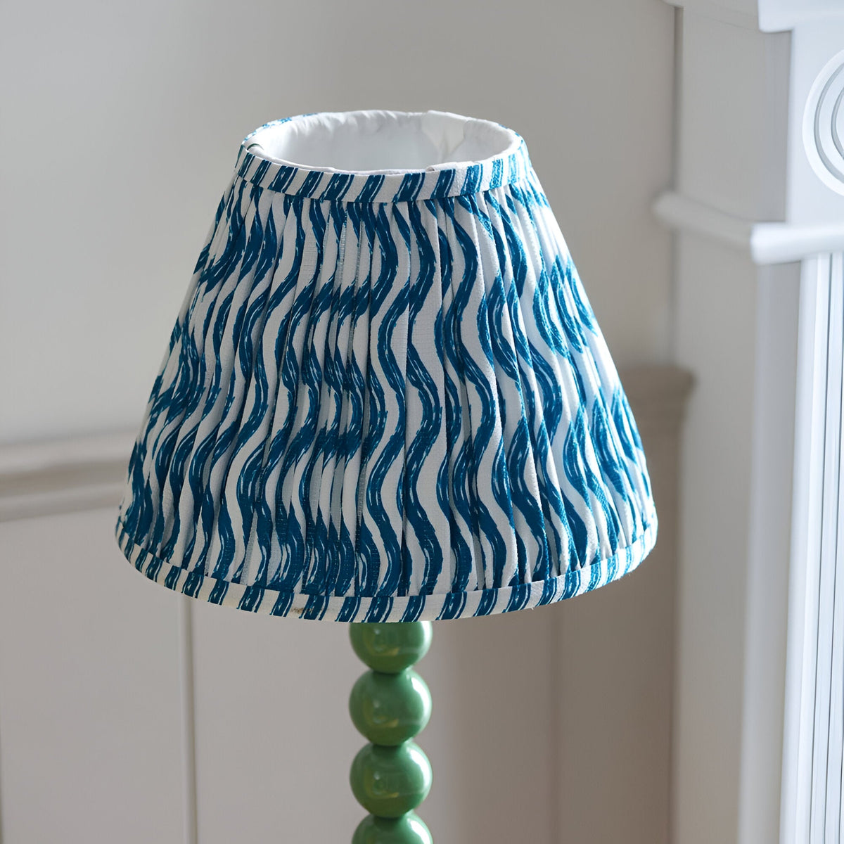 Endon Brenleigh Ripple table lamp with a pleated blue and white wave-print fabric shade above a glossy green stacked-sphere base.