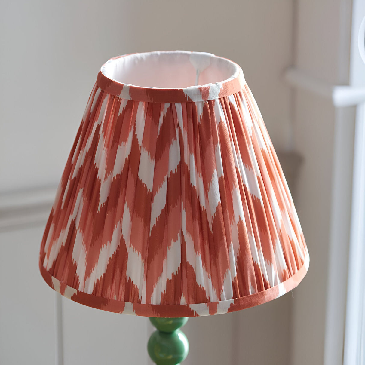 Brenleigh Zigzag Table Lamp with pleated terracotta and white zigzag-print shade on a green gloss stacked-sphere metal base.
