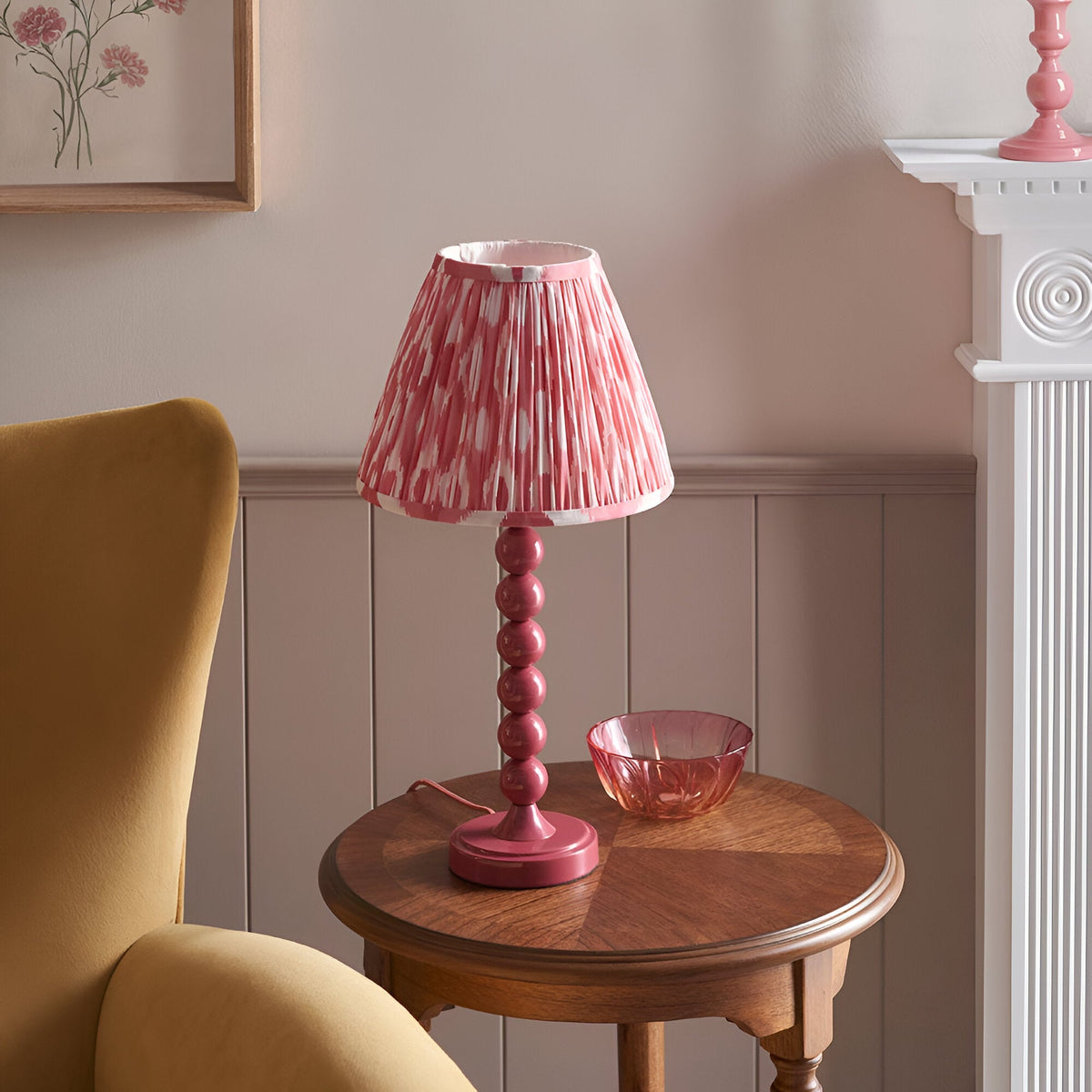 Endon Brenleigh Ikat pink table lamp with stacked-sphere gloss base and pleated ikat shade on a wooden side table beside a mustard armchair.