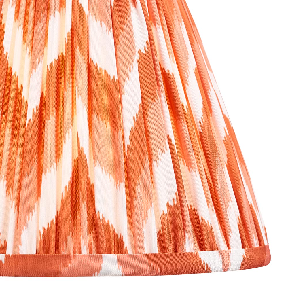Close-up of the Brenleigh Zigzag Table Lamp's pleated fabric shade in orange and white zigzag pattern with contrasting trim, shown on a white background.