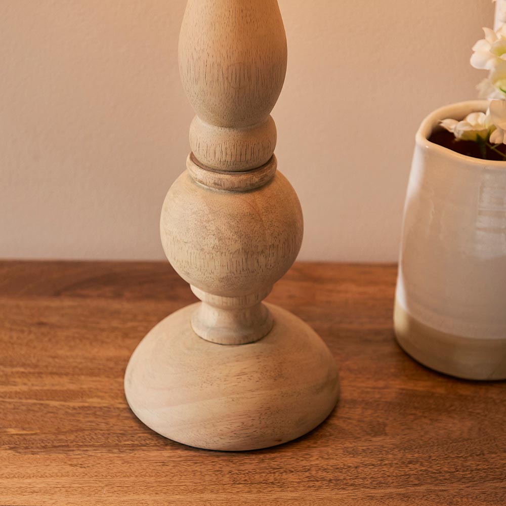 Brenhurst Table Lamp base close-up in natural wood with turned bulb and ball details, shown on a wooden surface beside a vase.