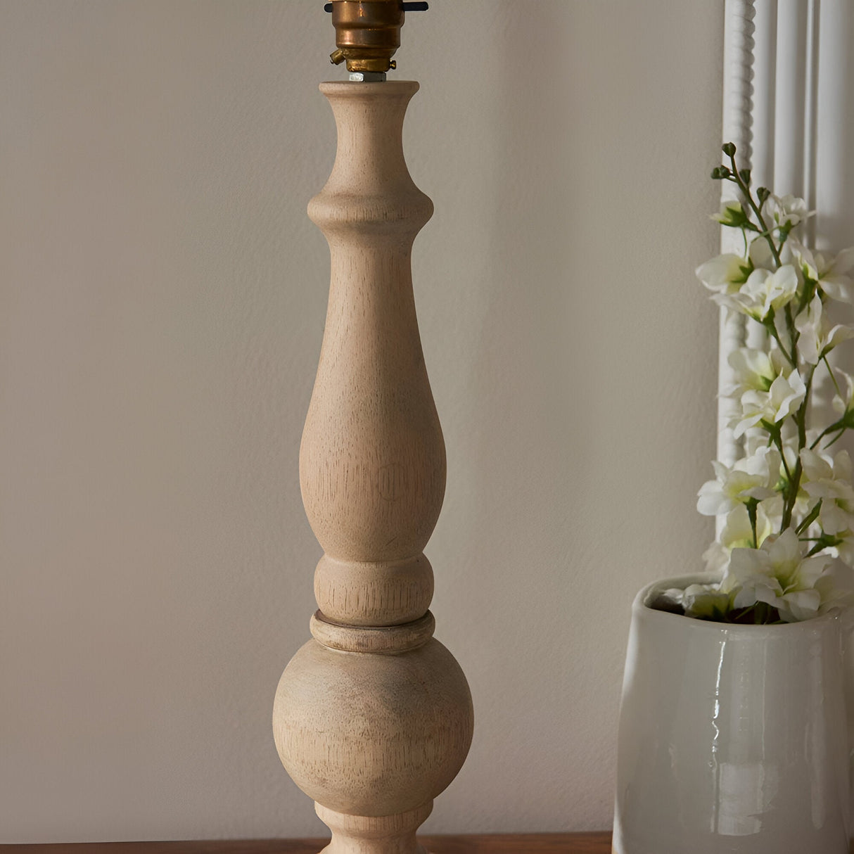 Brenhurst Table Lamp base in vintage white, hand-turned solid wood with a brass switched bulb holder, shown without shade against a plain wall.