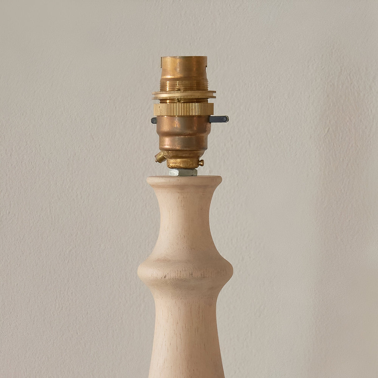 Brenhurst Table Lamp in Vintage White: close-up of the turned solid wood base with brass B22 bayonet lamp holder, shown against a plain light background.