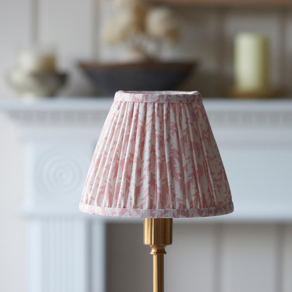 Endon Ashstead LED table lamp with a pleated pink leaf-print fabric shade on a brushed brass stem, shown on a mantel with a bowl and candle behind.