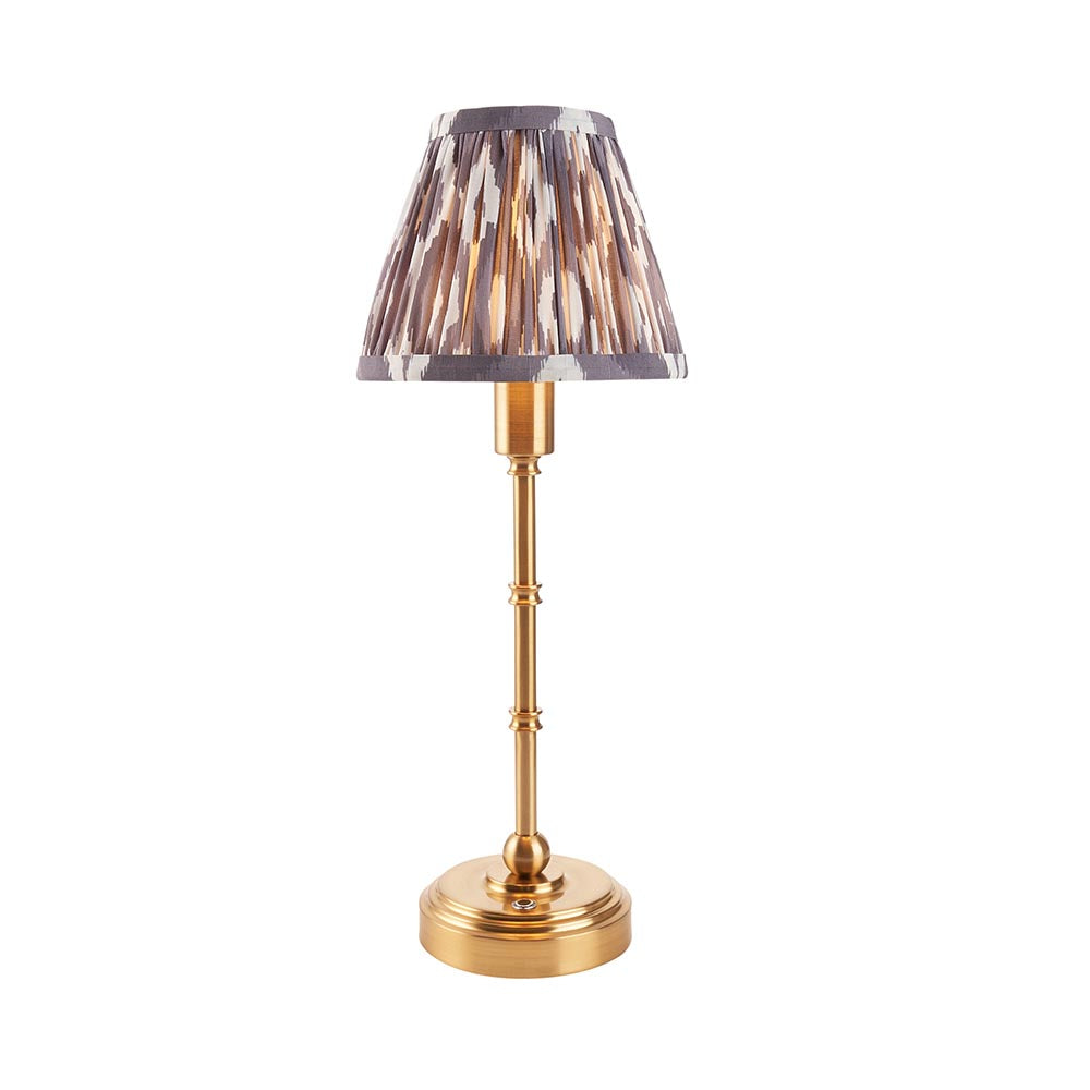 Ashstead LED table lamp with brass stem and base, topped by a pleated grey and white Ikat-print fabric shade, shown on a plain white background.