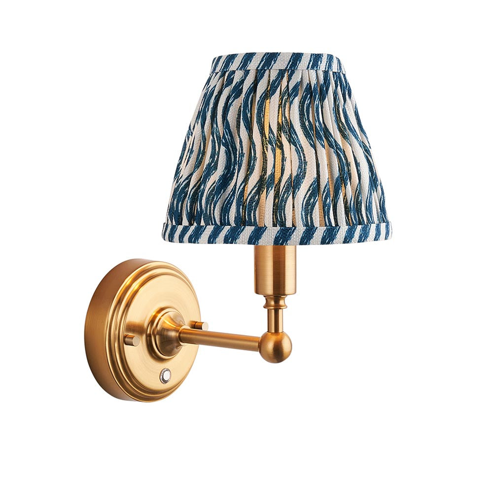 Ashstead LED Ripple wall light with brushed brass arm and round wall plate, pleated blue and white wave-print fabric shade, shown on a plain white background.