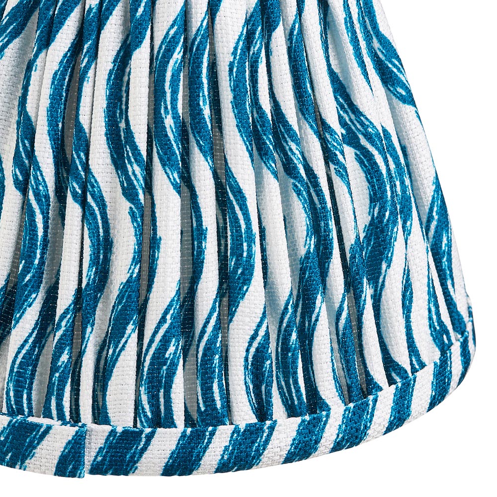 Close-up of the Ashstead LED Ripple Wall Light's pleated fabric shade, showing a blue wave print on white with brass trim detailing.