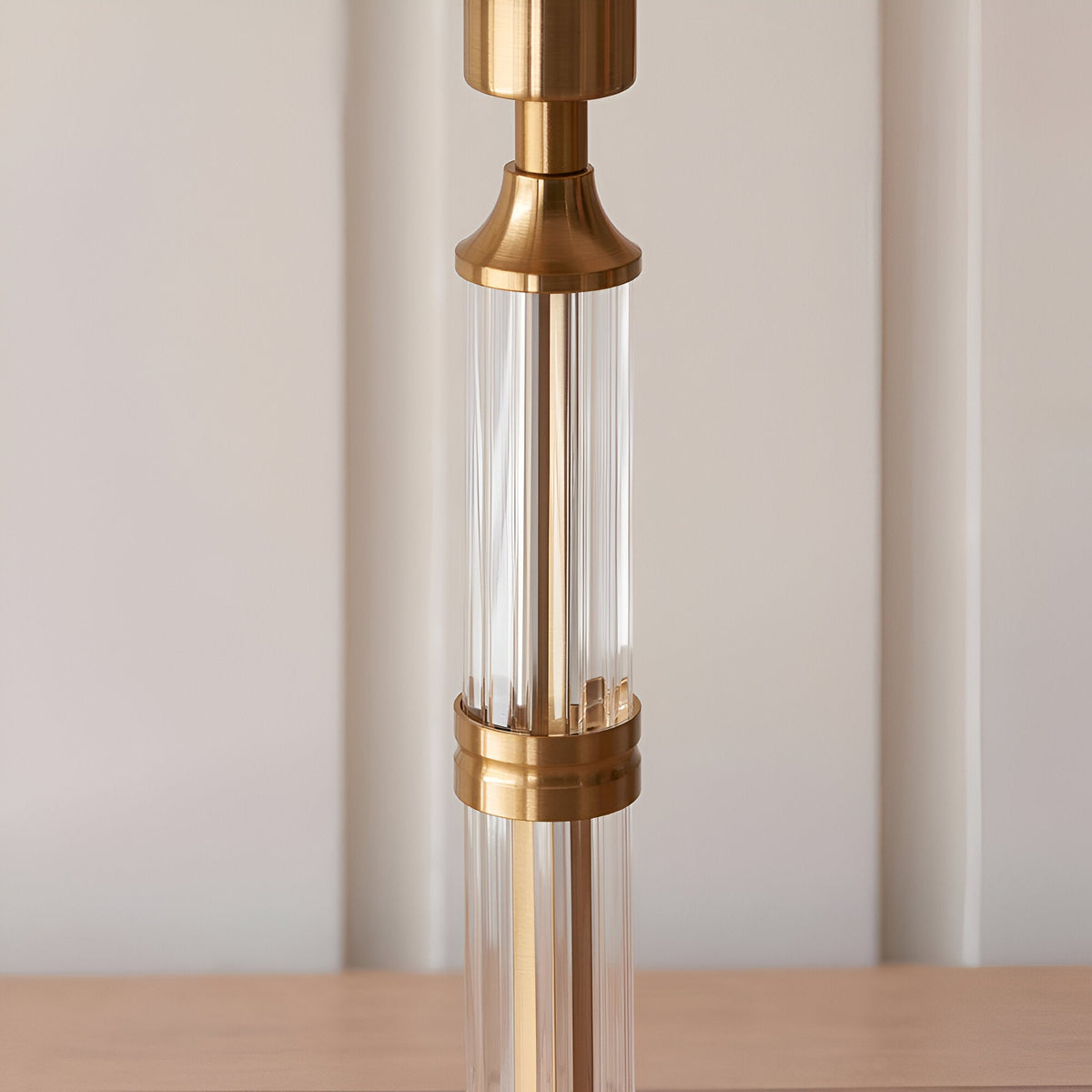 Close-up of the Endon Carlwood LED table lamp's stem, showing brushed aged brass fittings with clear ribbed acrylic detailing on a wooden surface.