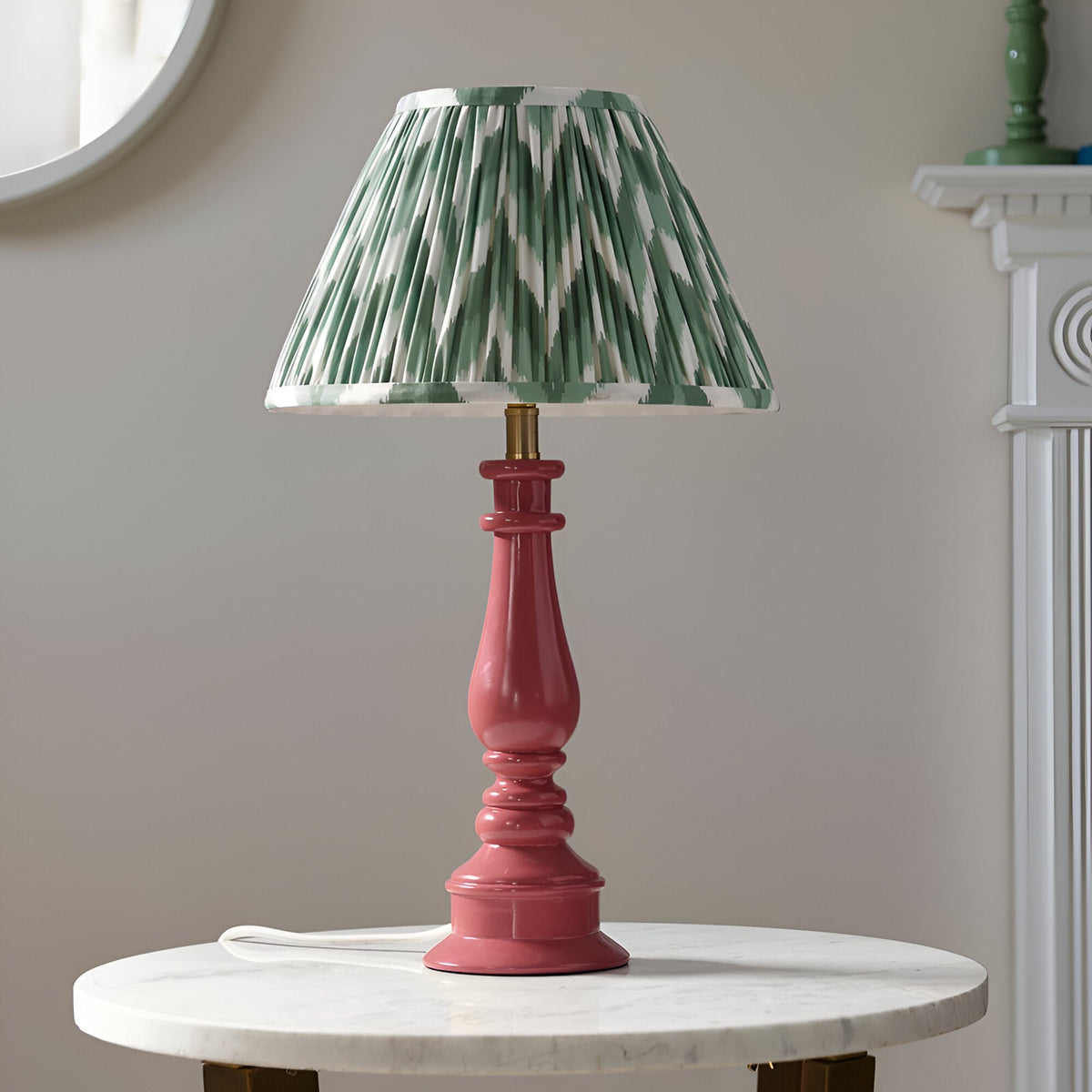 Endon Carlworth table lamp with turned pink resin spindle base and pleated green zigzag fabric shade, on a marble side table by a mirror.