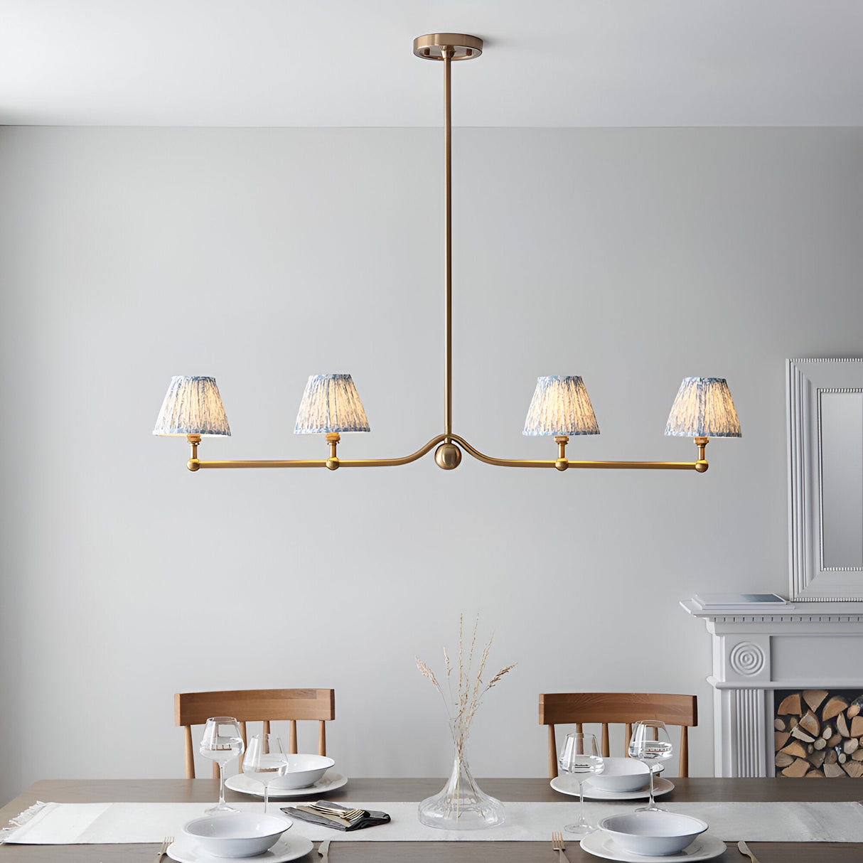 Endon Cliffleigh Leaf 4 light linear pendant in brushed brass with four tapered blue Leaf print shades, shown above a dining table.