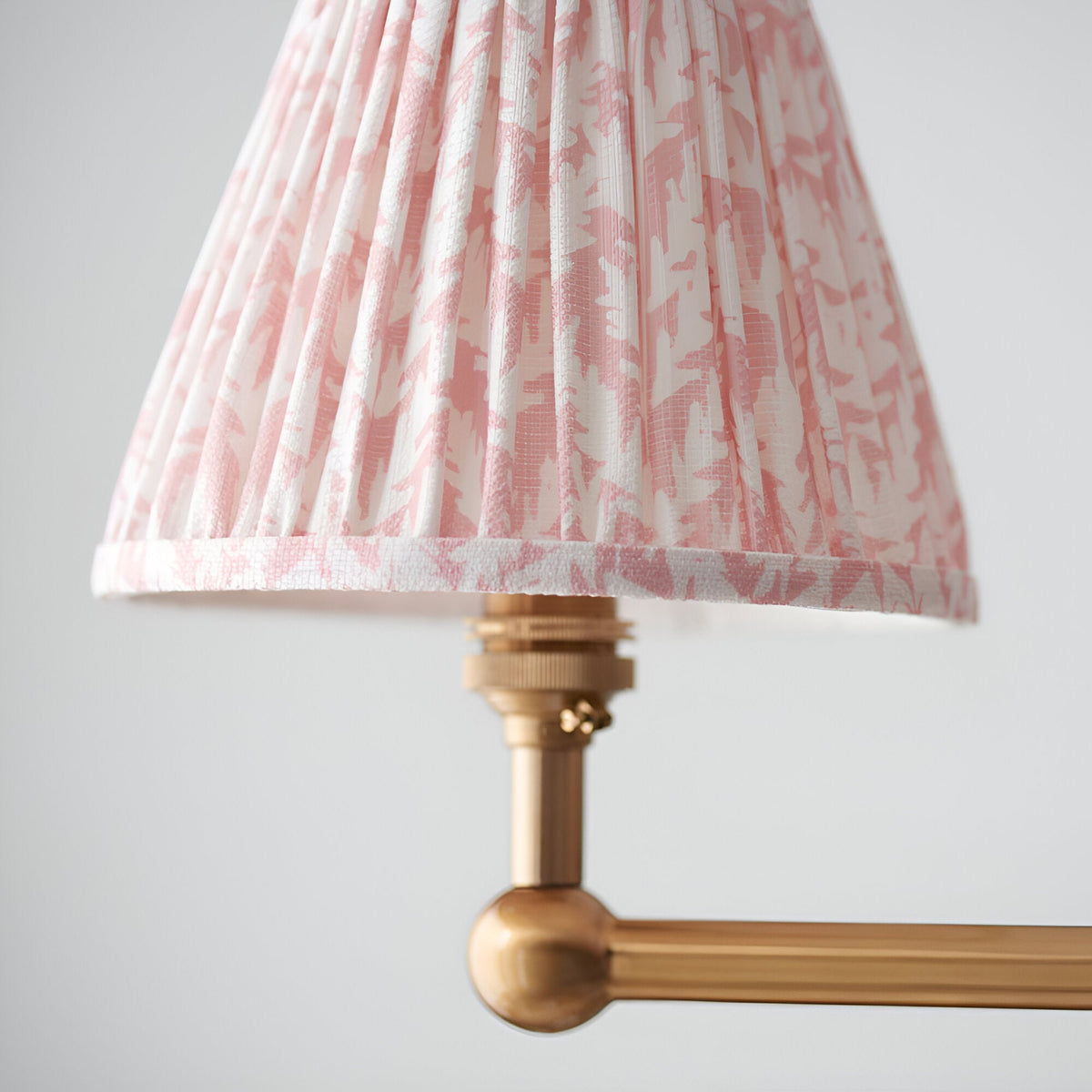 Close-up of the Cliffleigh Leaf 4 Light Linear Pendant, showing a pleated pink and white patterned fabric shade on a brushed brass bar with sphere detail.