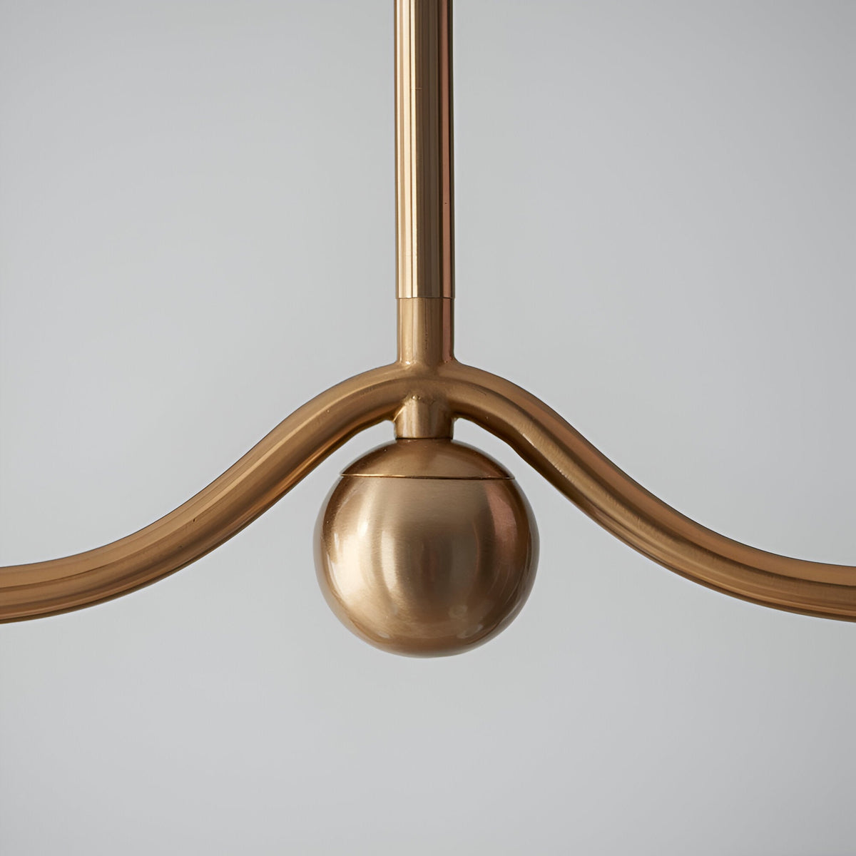 Close-up of the Cliffleigh Leaf 4-Light Linear Pendant in brushed aged brass, showing the central sphere detail and curved metal arms.
