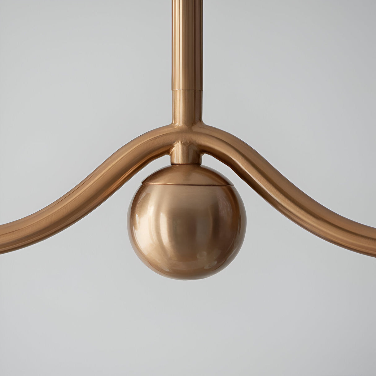 Close-up of Endon Cliffleigh pendant detail showing brushed aged brass curved arm junction with a polished sphere accent against a light background.