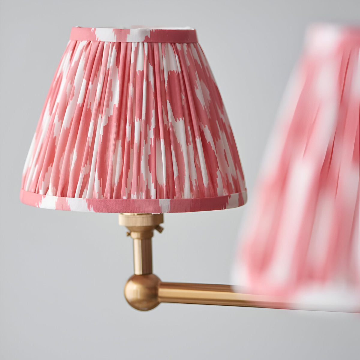 Endon Cliffleigh Ikat pendant shade in pleated coral pink and white faux silk with taped edging, mounted on a brushed aged brass arm.