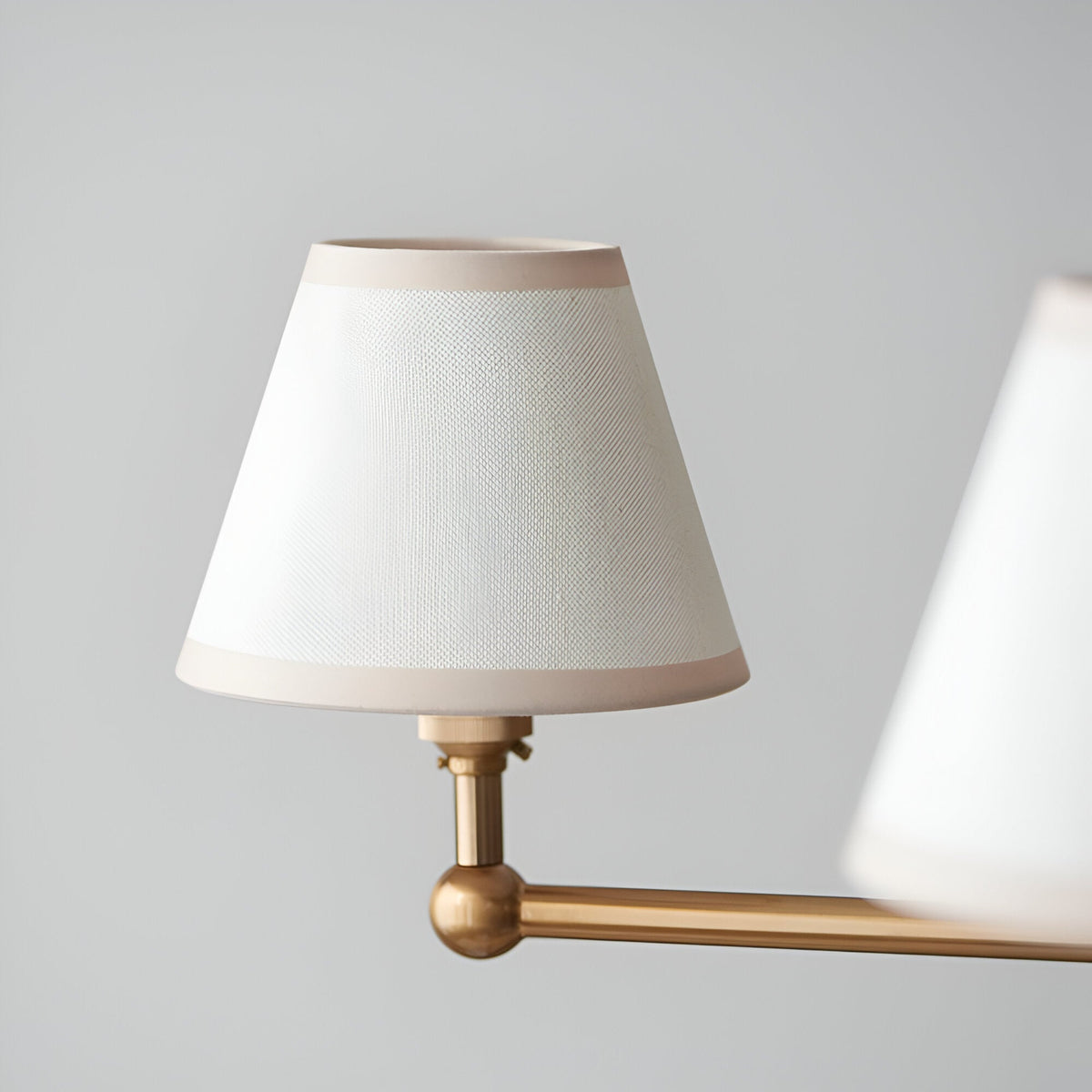 Close-up of an Endon Cliffleigh pendant shade in vintage white cotton mix with almond taped edges, mounted on a brushed aged brass arm.