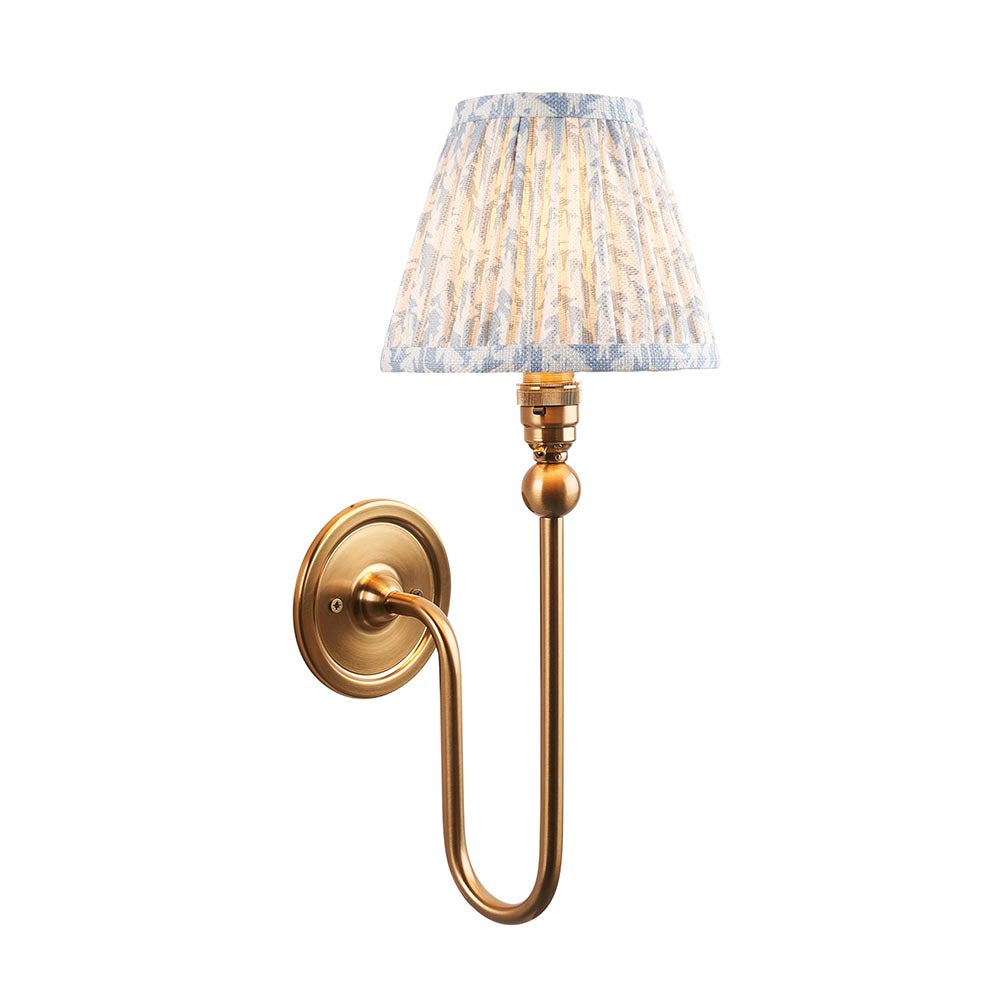 Endon Cliffleigh Leaf wall light in brushed brass with a curved arm and pleated blue leaf-print faux linen tapered shade, on a white background.