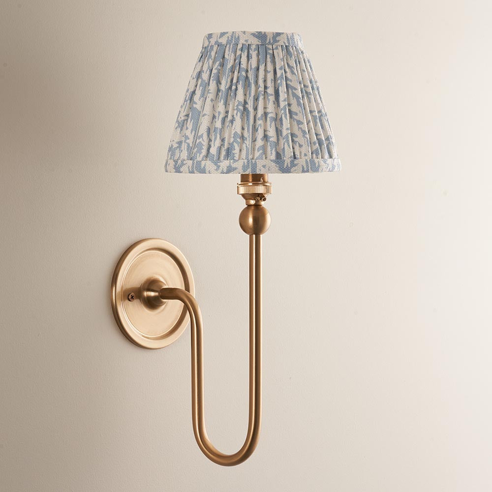 Endon Cliffleigh Leaf Wall Light II in brushed brass with a curved arm and pleated blue leaf-print fabric shade, mounted on a pale wall.
