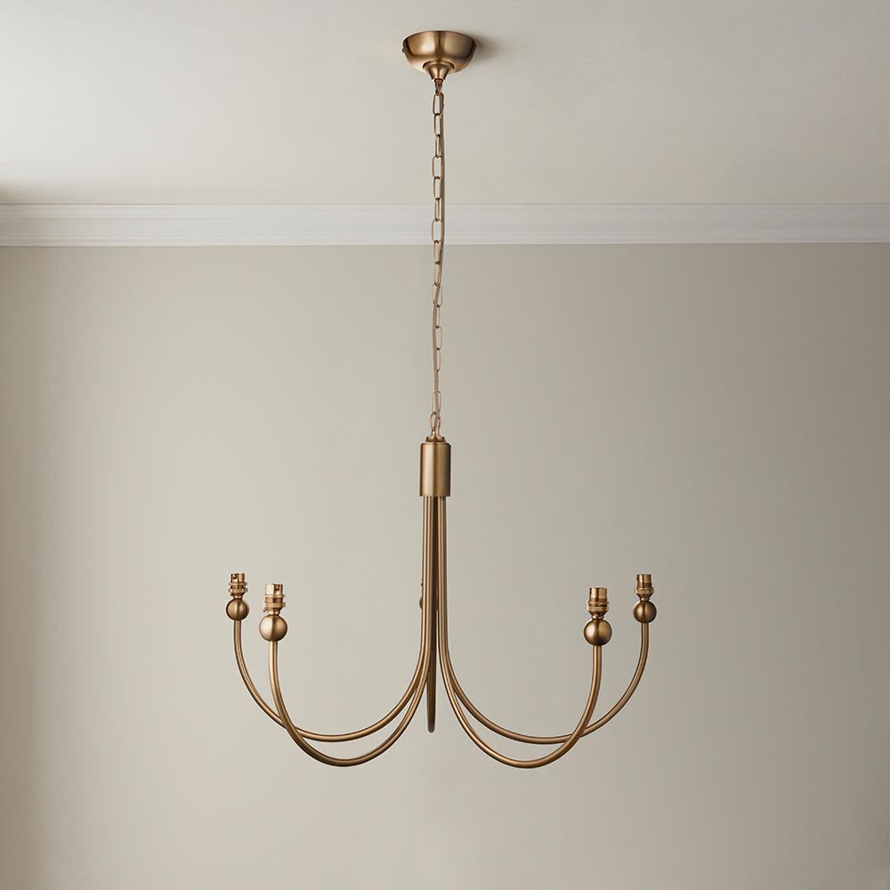 Cliffleigh Leaf 5-light curved arm pendant in brushed brass, hanging from a chain against a plain neutral wall.