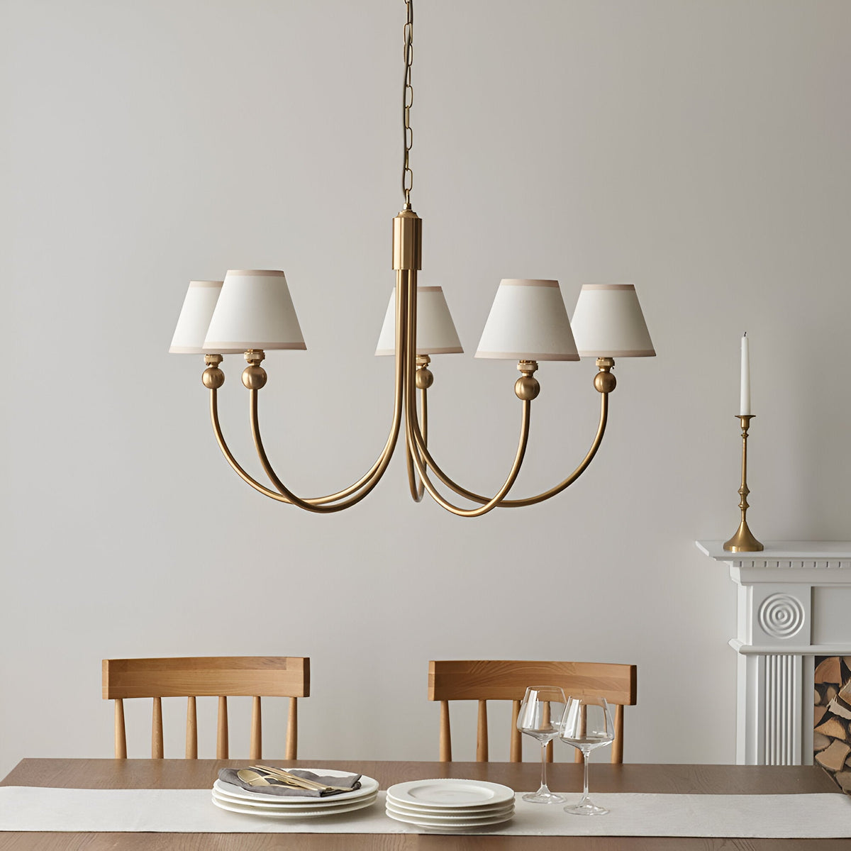 Cliffleigh 5 Light Curved Arm Pendant with brushed aged brass frame and tapered white fabric shades, shown above a dining table in a neutral-toned room.