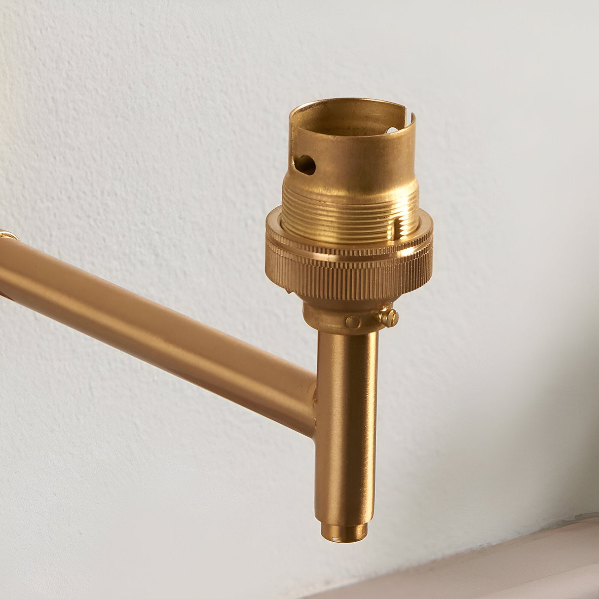 Close-up of the Endon Daneley Wall Light showing the brushed aged brass arm and authentic B22 lampholder against a white wall.