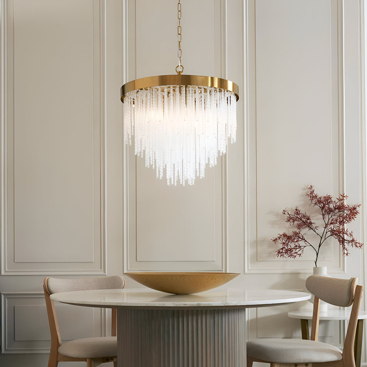Endon Aldfield 5 light pendant in brushed aged brass with tiered clear glass rods, hanging on a chain above a round marble dining table.