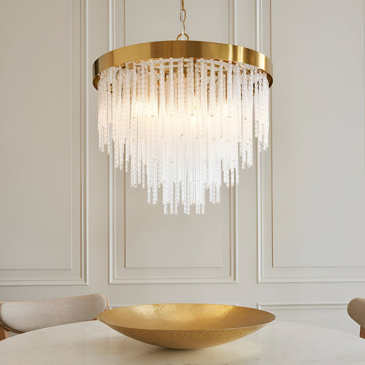 Endon Aldfield 5 light pendant with tiered clear glass rods and brushed aged brass frame, hanging above a gold bowl on a dining table.