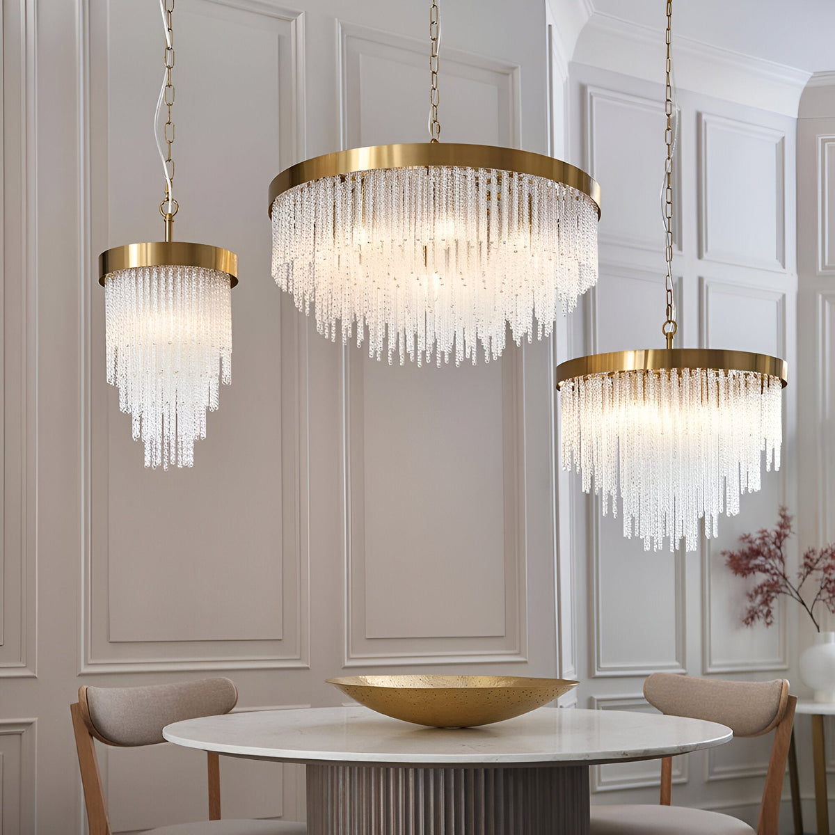 Endon Aldfield pendant lights in brushed brass with tiered clear glass rods, shown in three sizes above a round marble dining table.