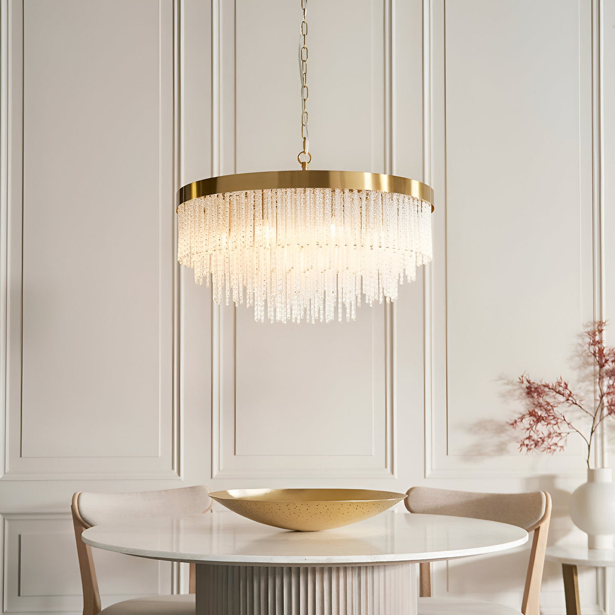 Aldfield nine-light pendant with tiered clear glass rods in a brushed aged brass frame, hung above a marble dining table in a light-panelled room.