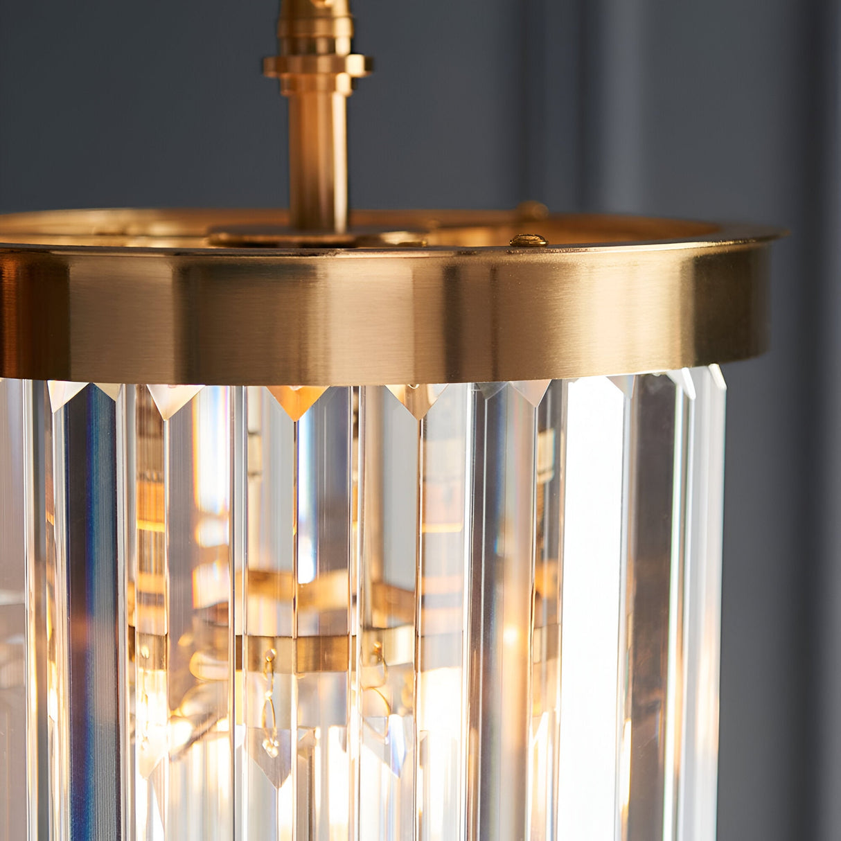 Close-up of the Endon Bevstead pendant showing its brushed aged brass frame and tiered cascade of clear lozenge-shaped glass drops.