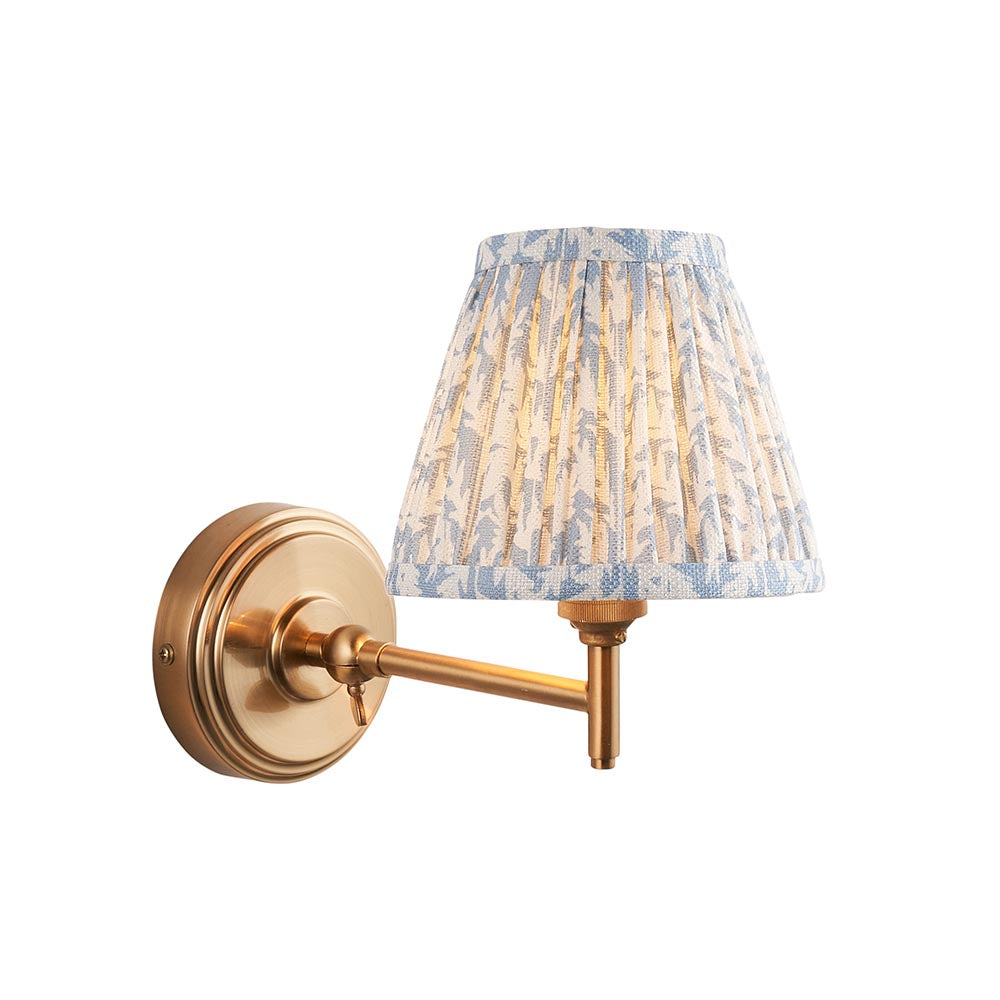 Endon Cliffwood Leaf wall light with brushed aged brass stepped backplate, adjustable arm and pleated blue leaf-print fabric shade on a white background.