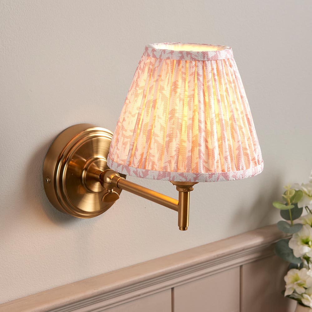 Cliffwood Leaf Wall Light in brushed brass with an adjustable arm and pleated pink leaf-print fabric shade, shown mounted on a light grey wall.