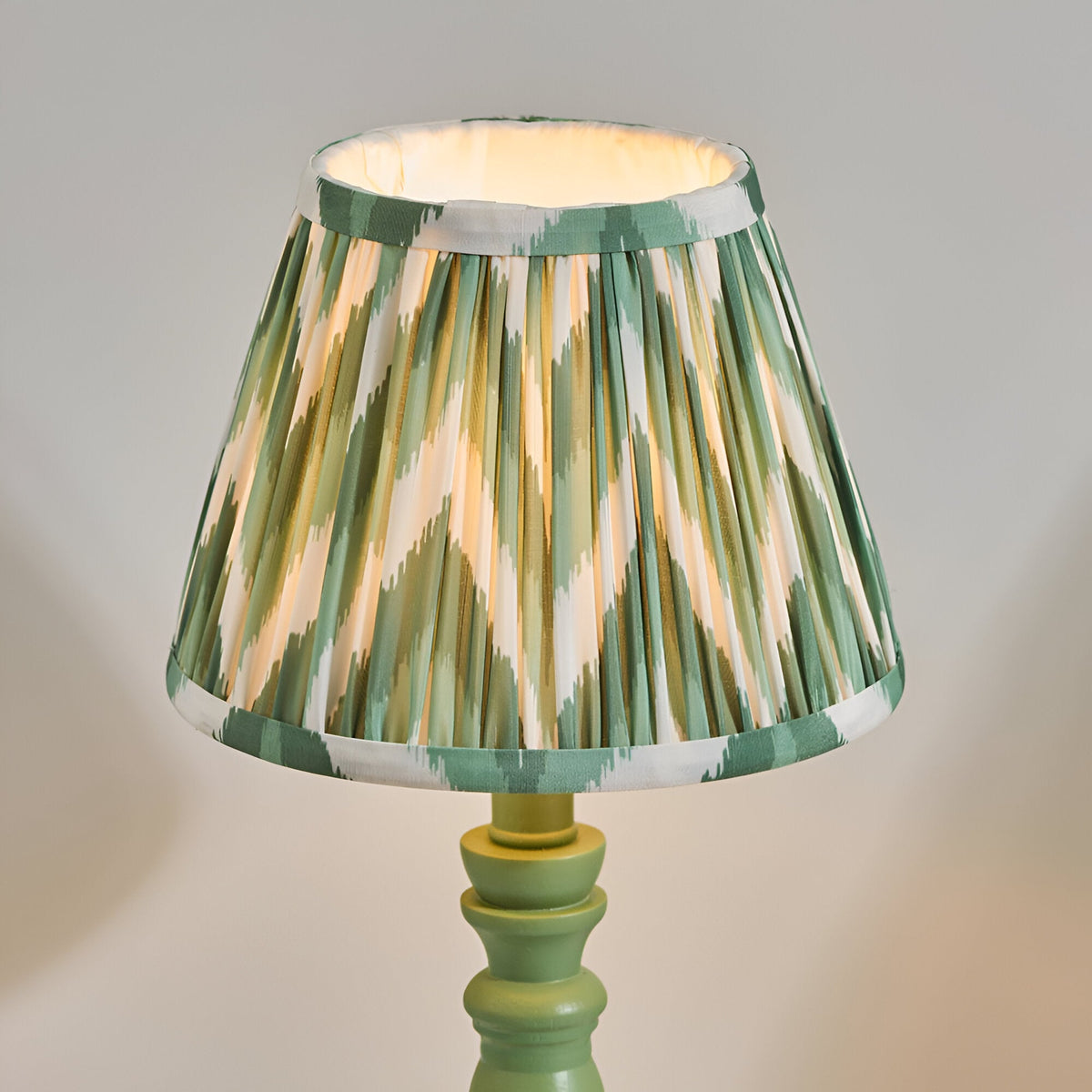 Endon Aldworth table lamp with green turned wood spindle base and handmade pleated Zigzag faux silk shade in green, olive and cream.