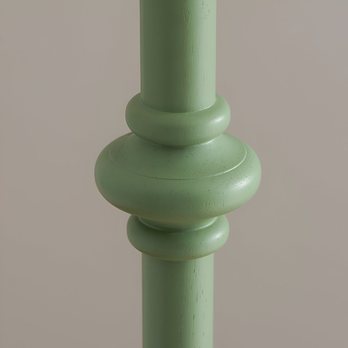 Close-up of the Bevbury Zigzag Floor Lamp's turned wooden spindle stem in green paint, showing a bulbous knop detail against a plain background.