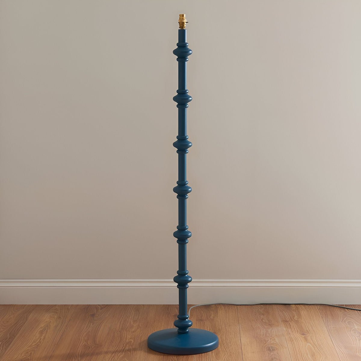 Endon Bevbury Ripple floor lamp base in blue turned wood with spindle detailing and brass B22 holder, shown on wood flooring against a neutral wall.