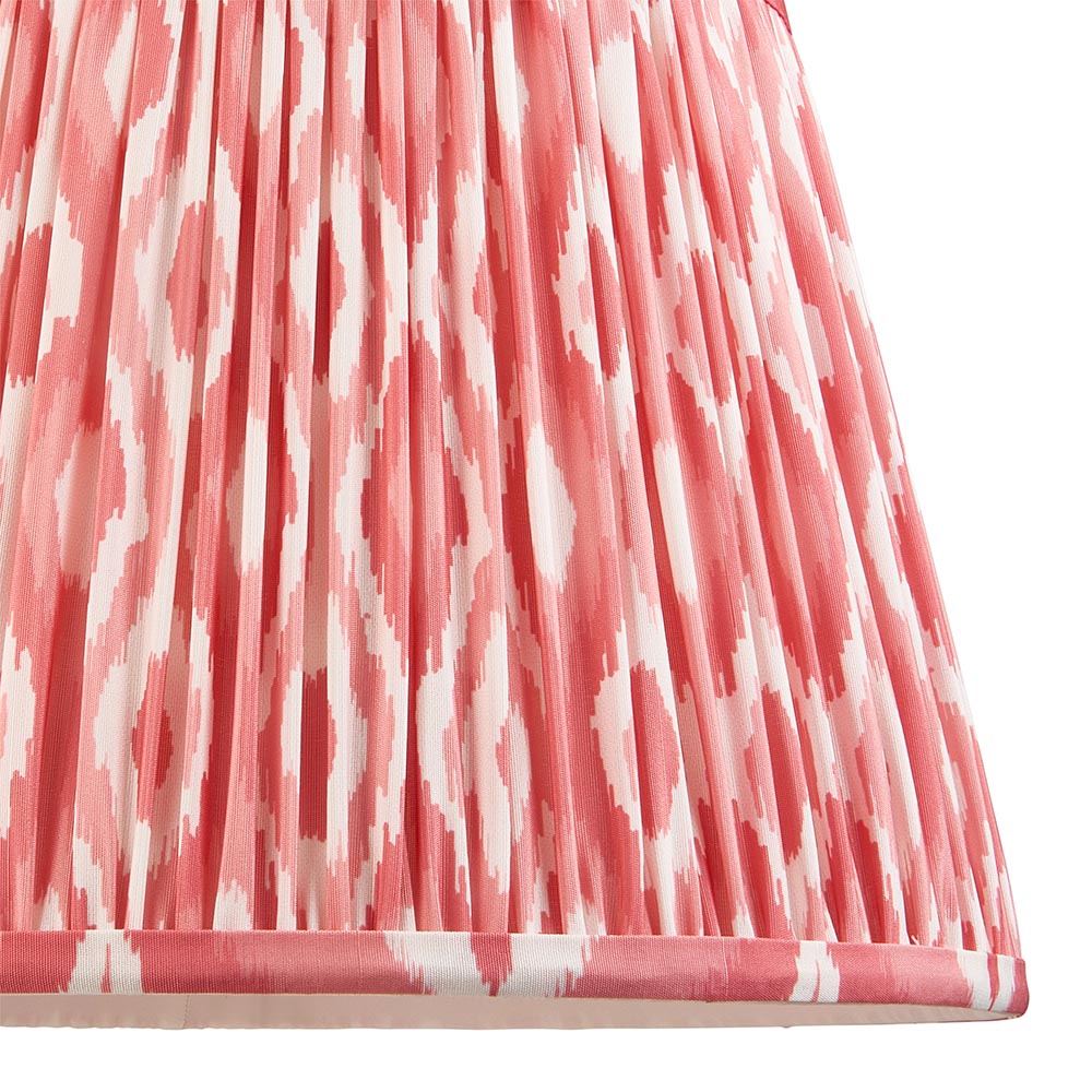 Close-up of the Brenleigh Ikat floor lamp's pleated fabric shade in pink and white ikat pattern with a taped edge trim, shown on a white background.