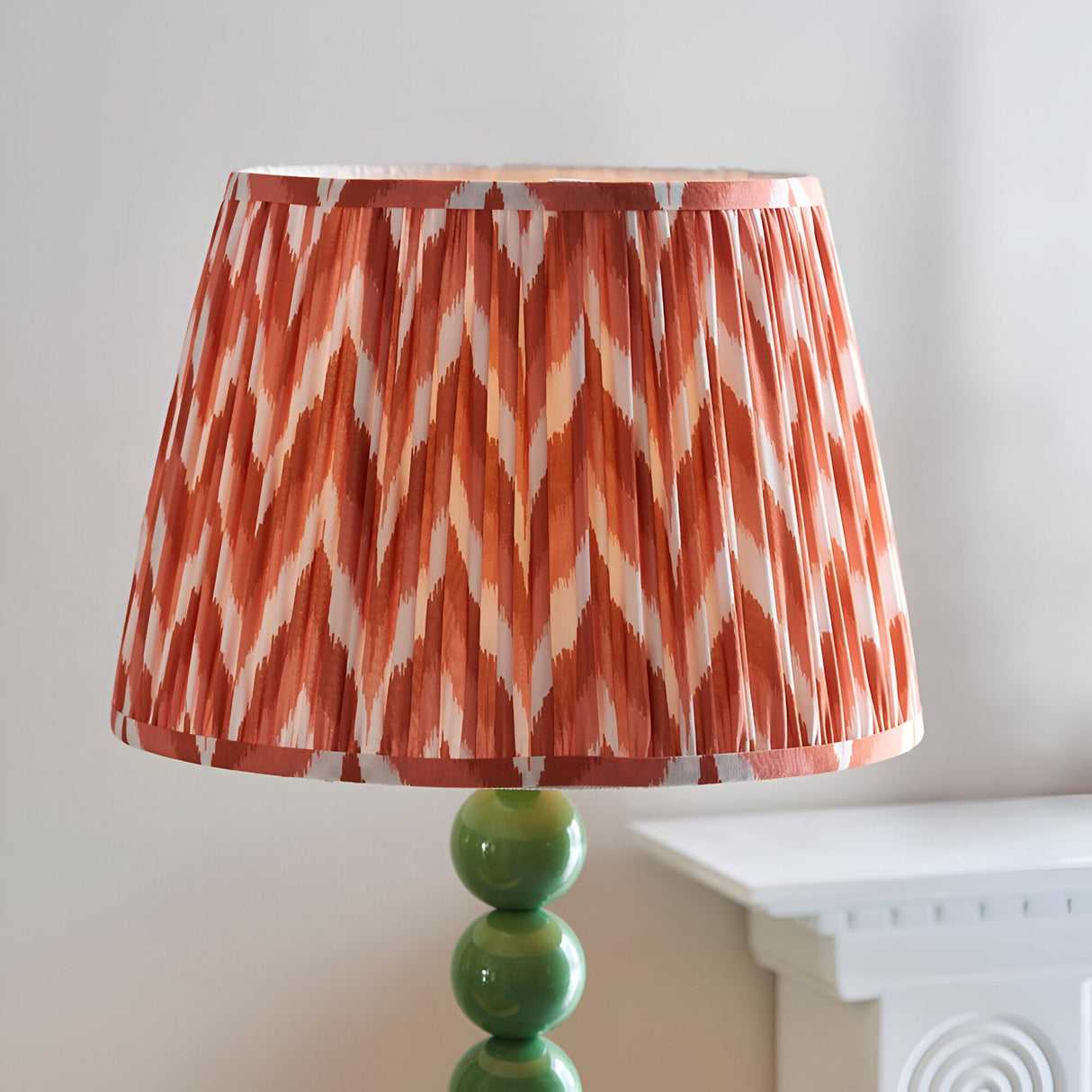 Brenleigh Zigzag Floor Lamp with green gloss stacked sphere base and pleated rust-orange zigzag print shade, shown against a plain light background.