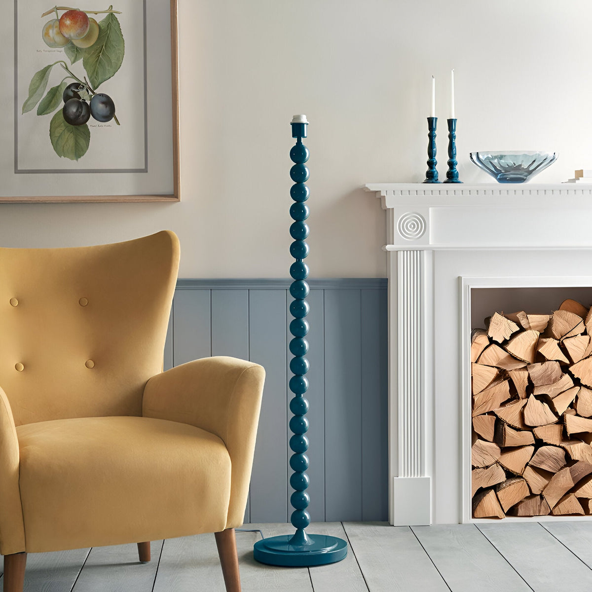 Brenleigh Zigzag floor lamp with teal stacked-sphere metal base and round foot, shown beside a mustard armchair in a living room without its patterned shade.