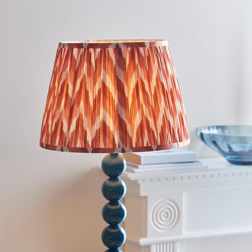 Endon Brenleigh floor lamp with a stacked blue gloss sphere base and orange zigzag pleated faux silk shade, beside a white mantel with a blue bowl.