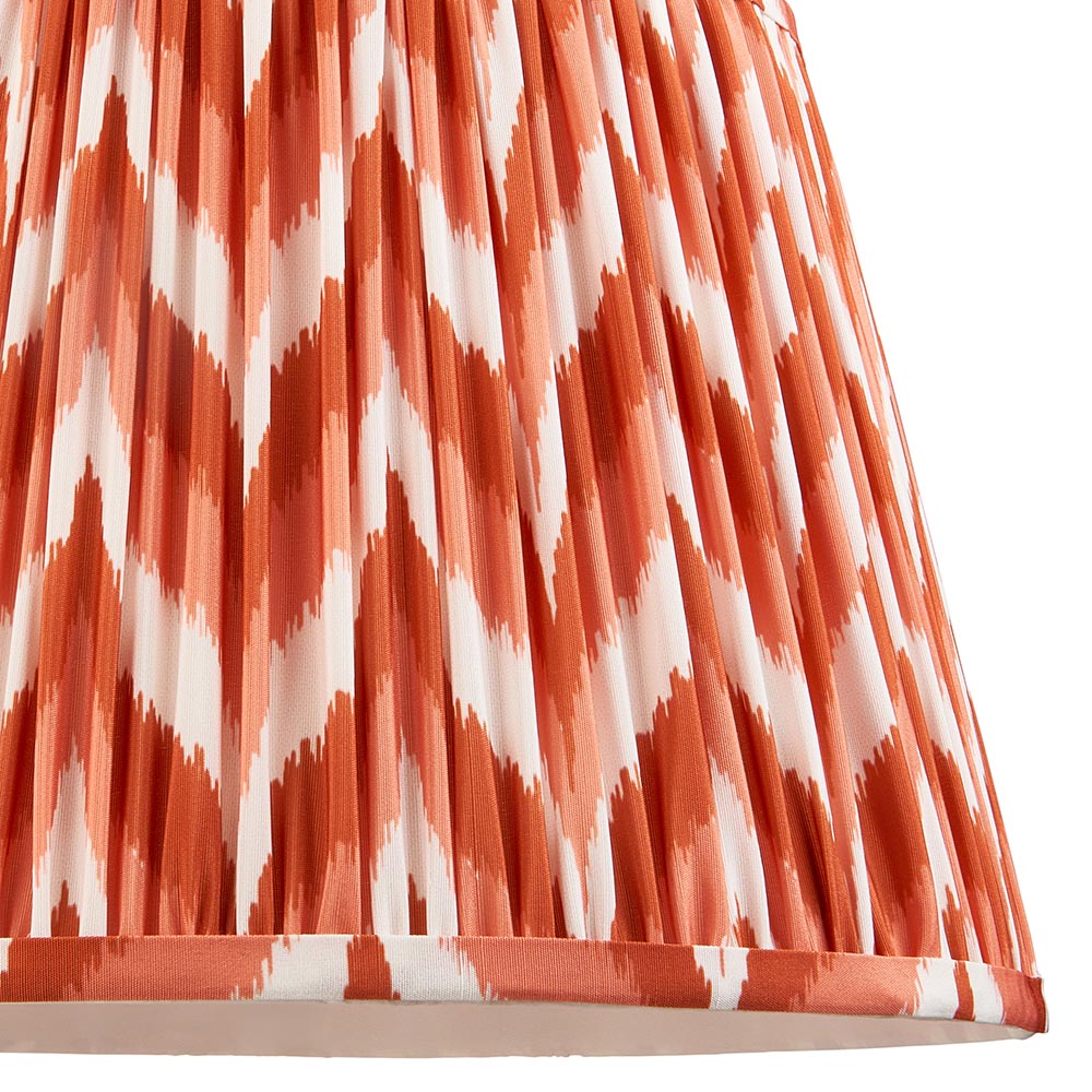 Close-up of the Endon Brenleigh Zigzag floor lamp shade, a gathered pleat faux silk in orange and white zigzag pattern with taped edge detailing.