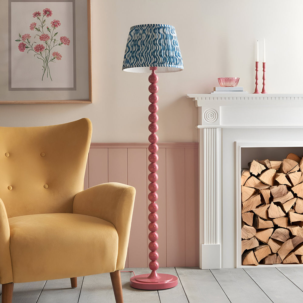 Endon Brenleigh Ripple floor lamp with pink stacked sphere base and blue rippled shade beside a yellow armchair and log-filled fireplace.