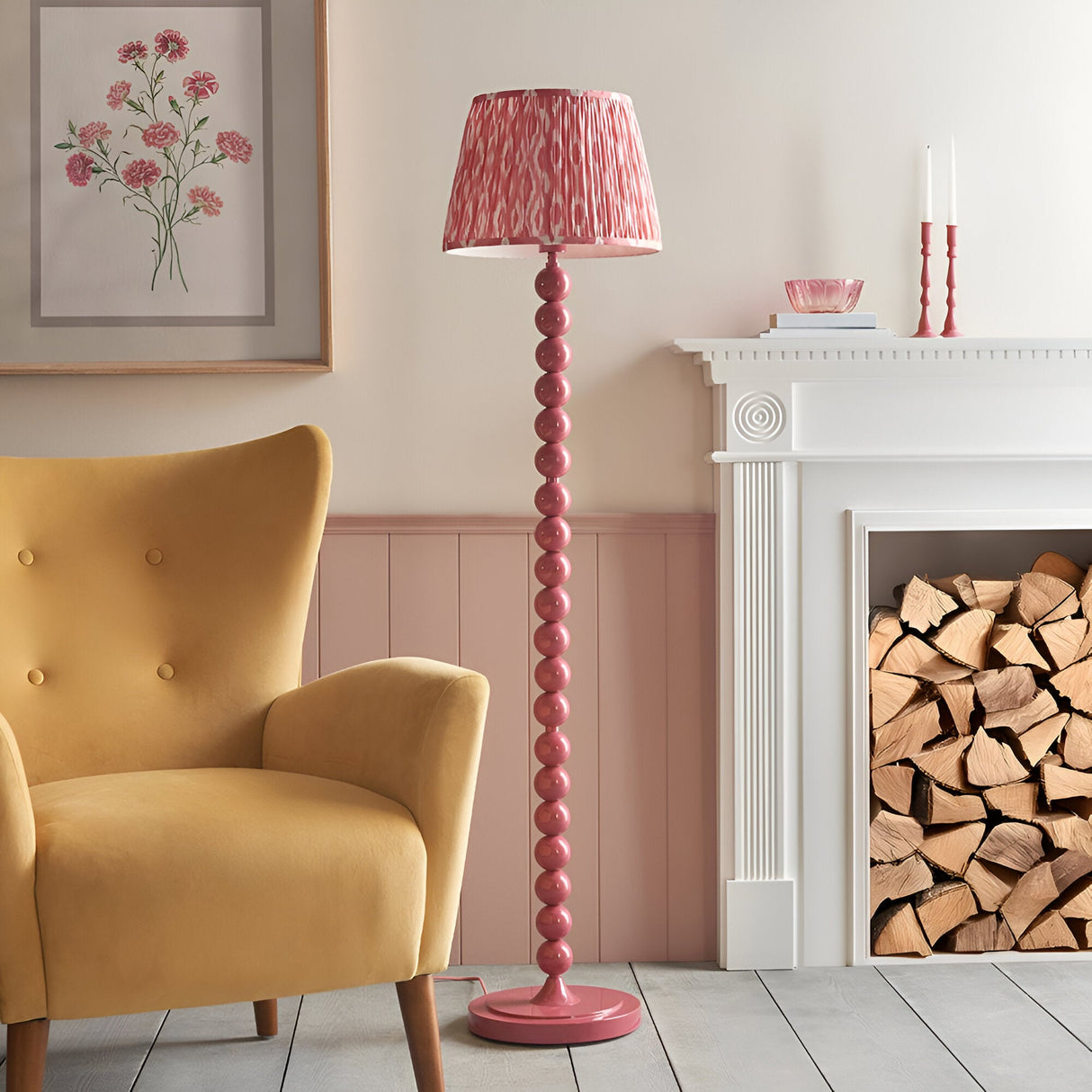 Endon Brenleigh pink stacked sphere floor lamp with Ikat pleated shade beside a mustard armchair and white fireplace in a pink-panelled living room.