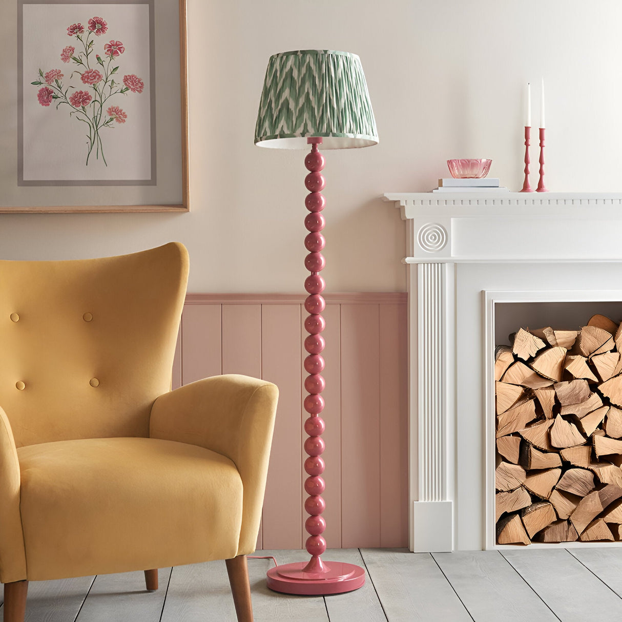 Endon Brenleigh floor lamp with pink stacked sphere base and green zigzag pleated shade, beside a yellow armchair and white fireplace with logs.