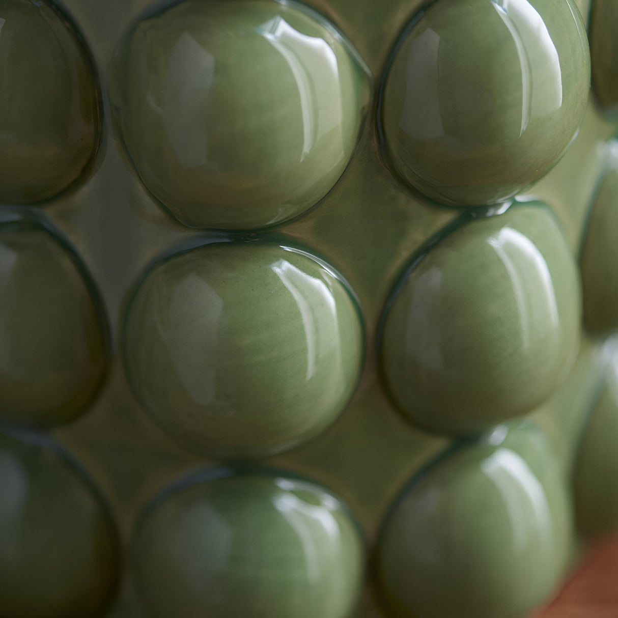 Close-up of the Endon Amberley Ripple table lamp's ceramic base showing rows of glossy olive green bobbles.