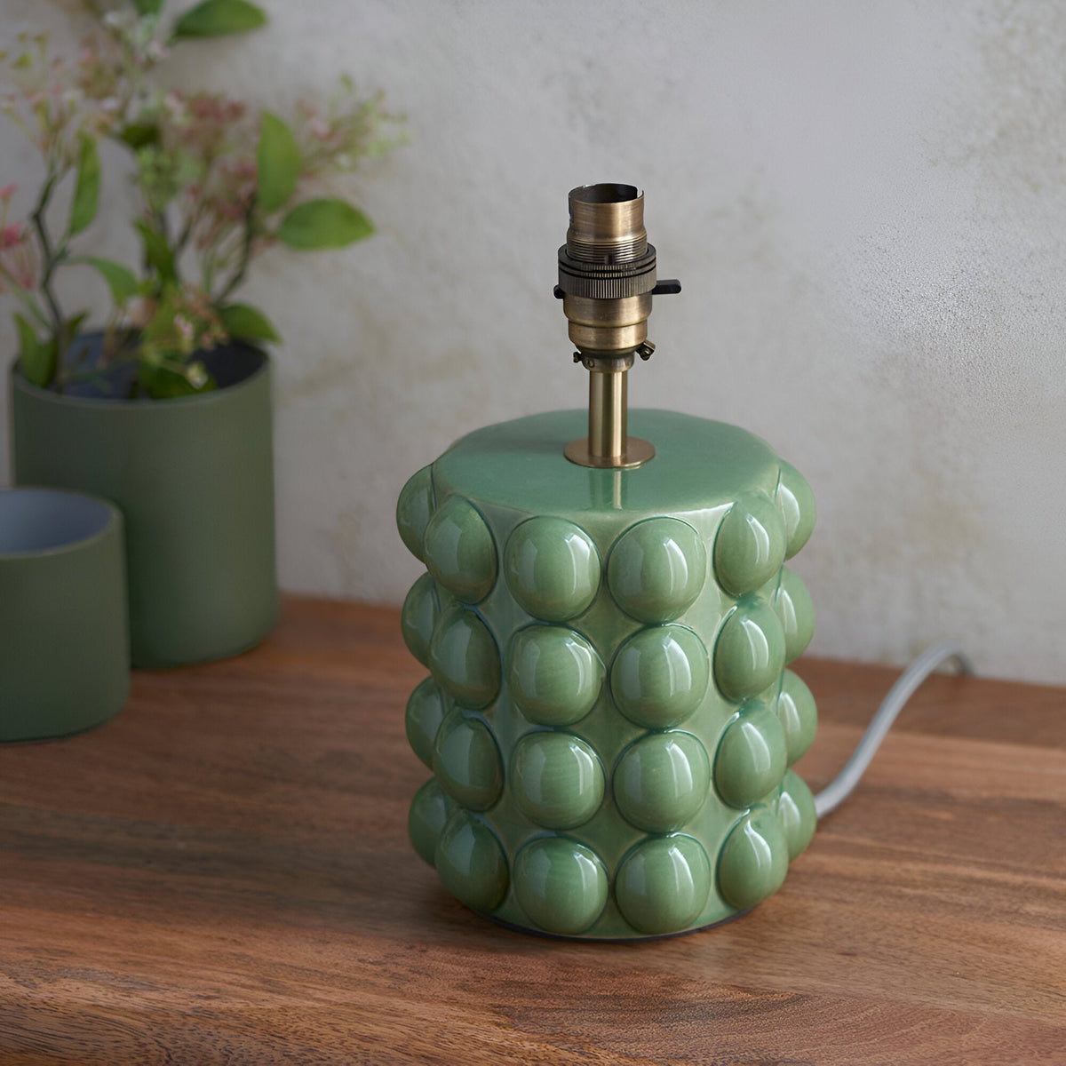 Endon Amberley table lamp base in glossy olive green glazed ceramic with sculpted bobble texture, aged brass B22 holder and stem, on a wooden surface.